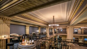 Un interior majestuoso con detalles ornamentales en el techo, una exhibición de barriles de vino y una escalera que conecta varios niveles.
