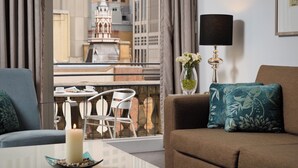 Una sala moderna con un sofá, una mesita con una vela, una lámpara y vistas de la ciudad a través de amplias ventanas.