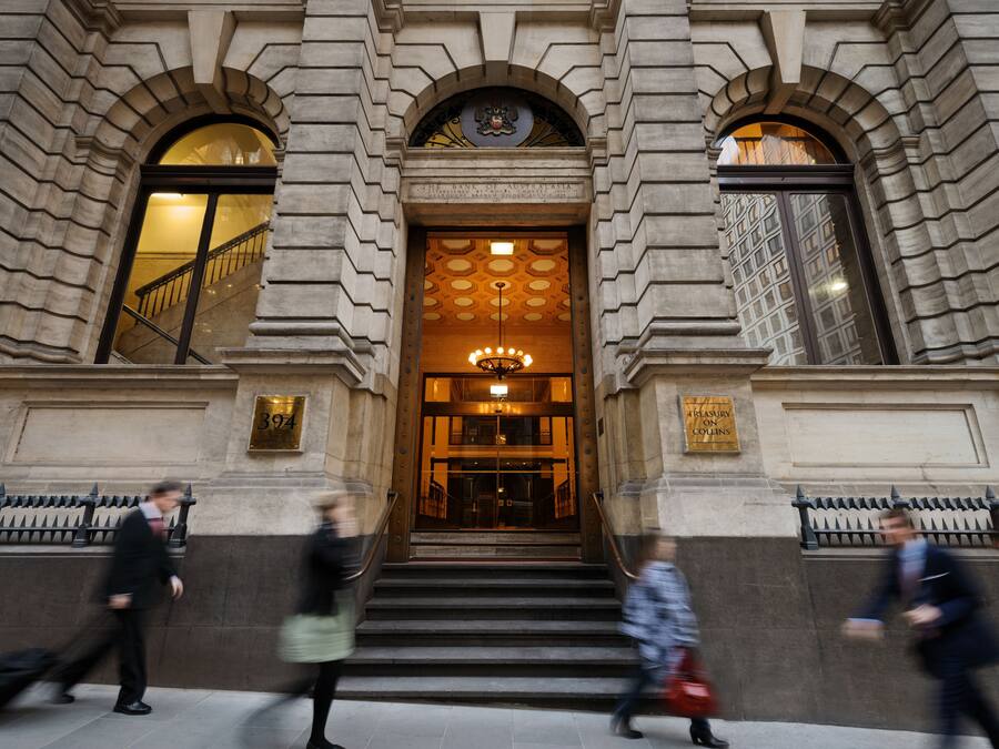 Uma entrada imponente com uma escadaria que leva a um hall, com janelas em arco e teto decorativo.