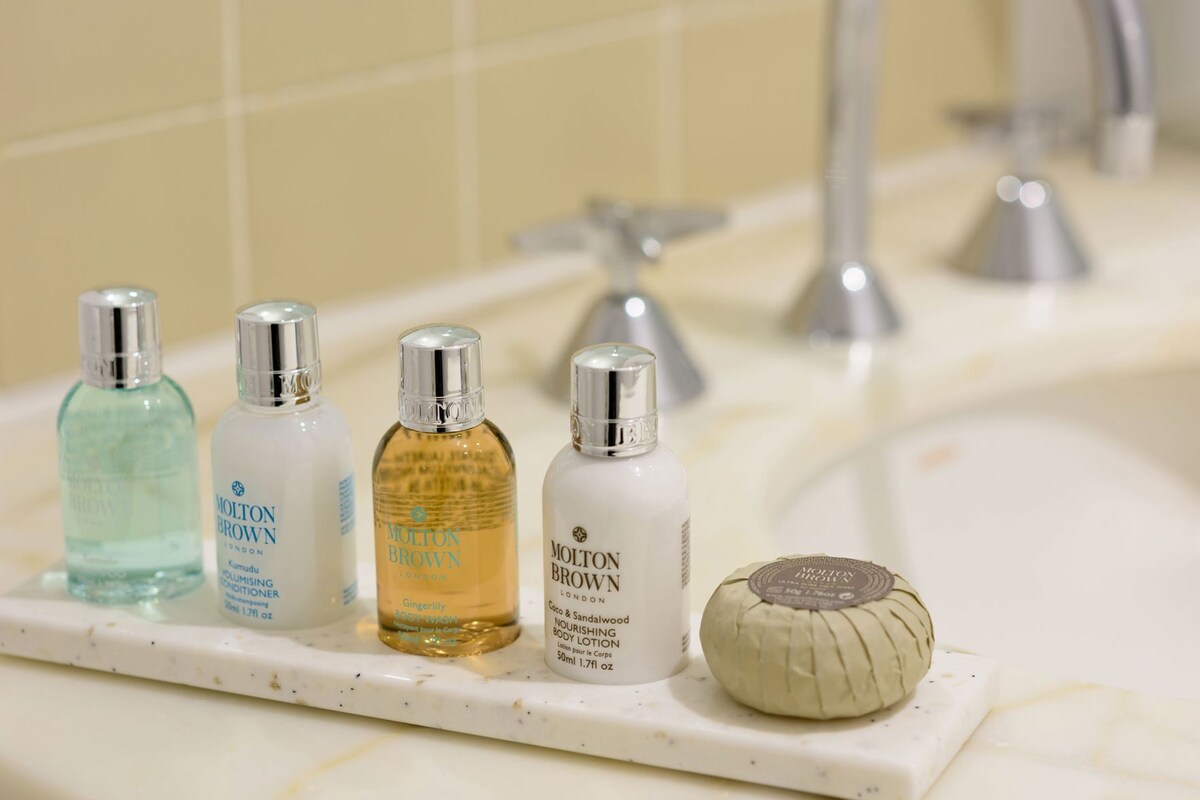 A bathroom shelf with four bottles of Molton Brown products and a soap bar.