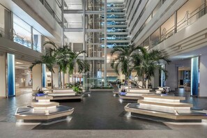 A spacious atrium with multiple floors, palm trees, and a central staircase. - Renaissance Resort Okinawa (Onna)