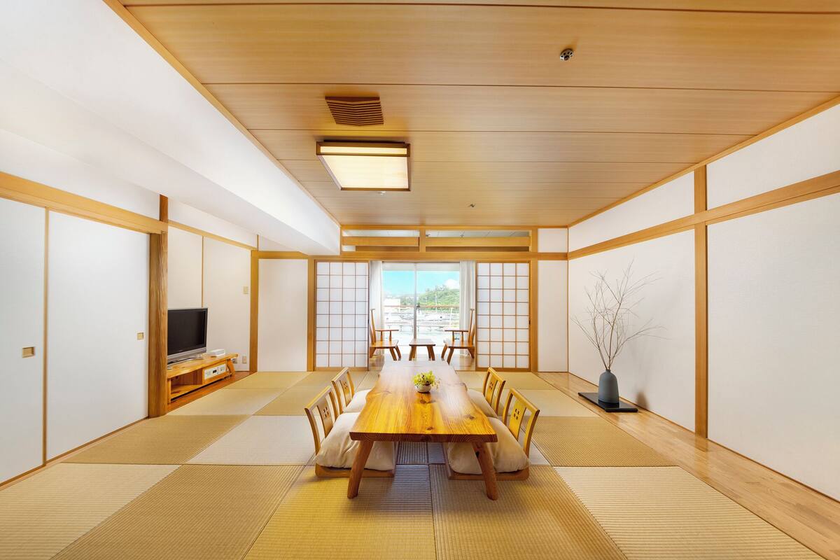 Una habitación japonesa tradicional con suelo de tatami, una mesa de madera baja y puertas correderas shoji.