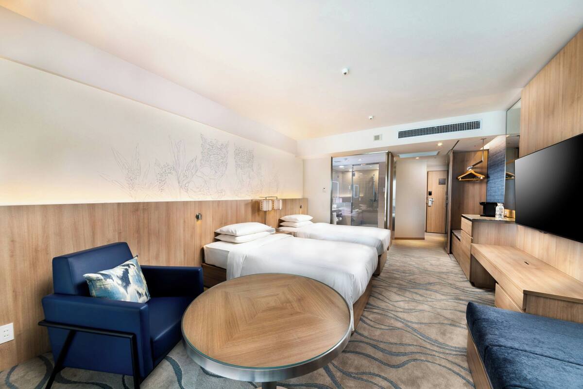 Una habitación de hotel con una cama, un sofá, una mesa redonda y un televisor.