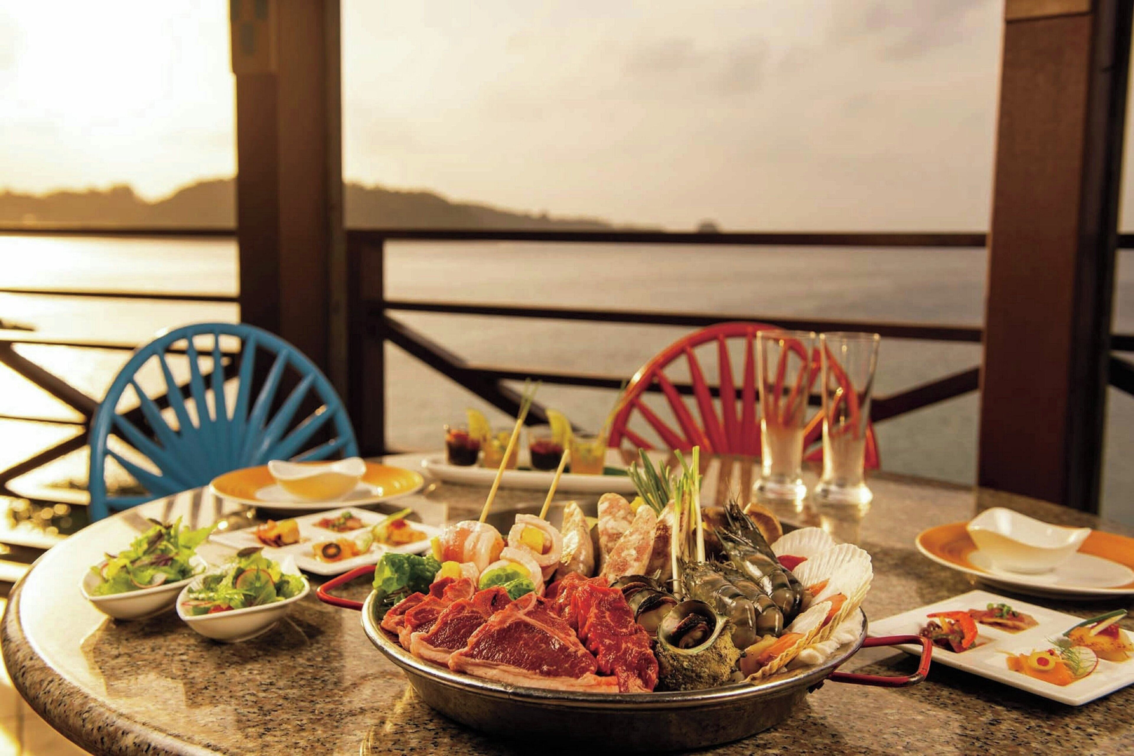 A dining table with seafood and salads, overlooking a body of water.