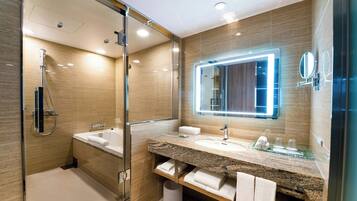 A modern bathroom with a glass-enclosed shower, a large mirror, and a granite countertop.