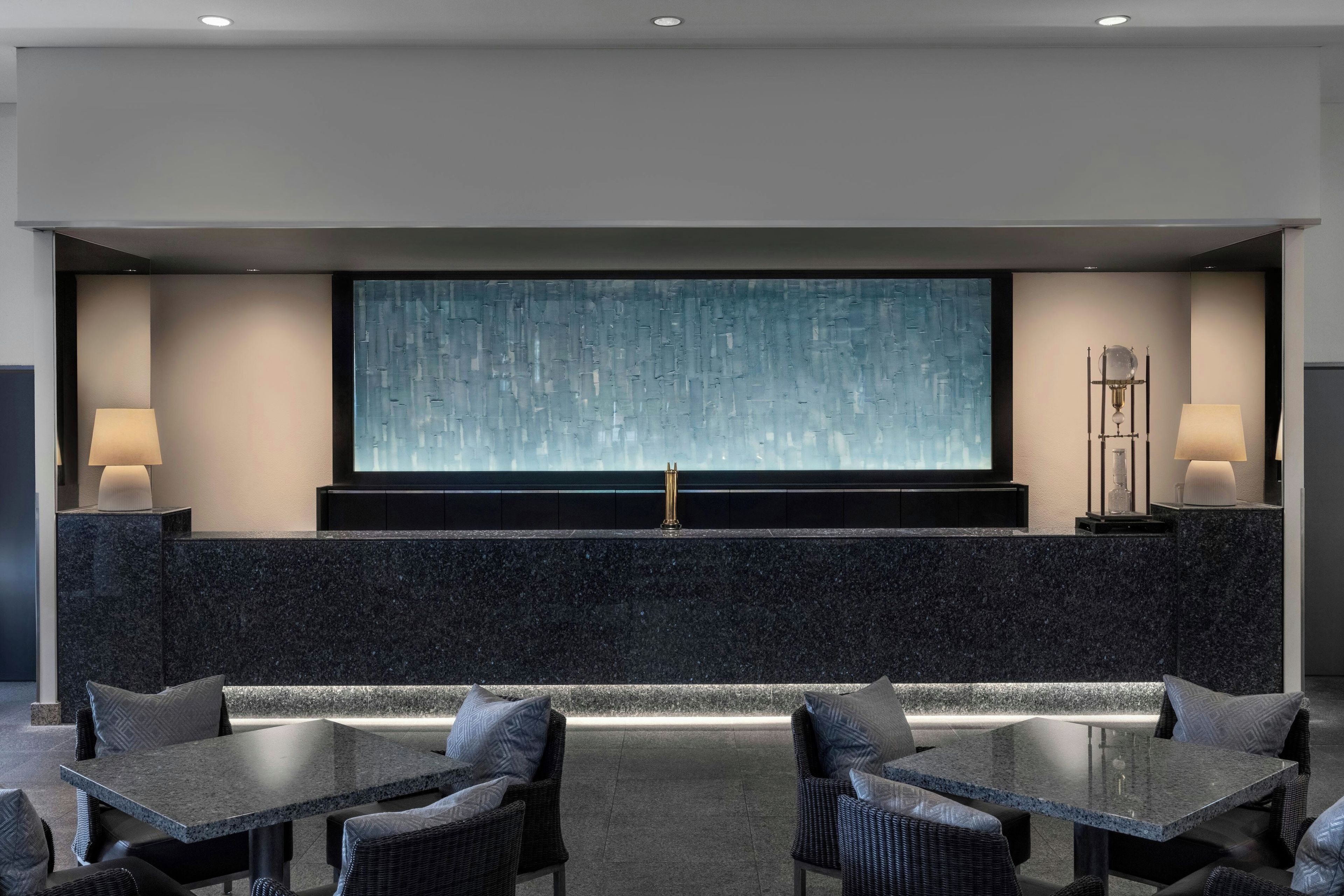 Un moderno vestíbulo de hotel con una pantalla grande, zona de estar e iluminación ambiental.