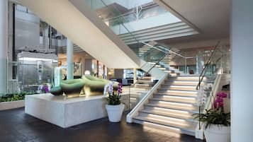 A modern interior with a staircase, seating areas, and potted plants.