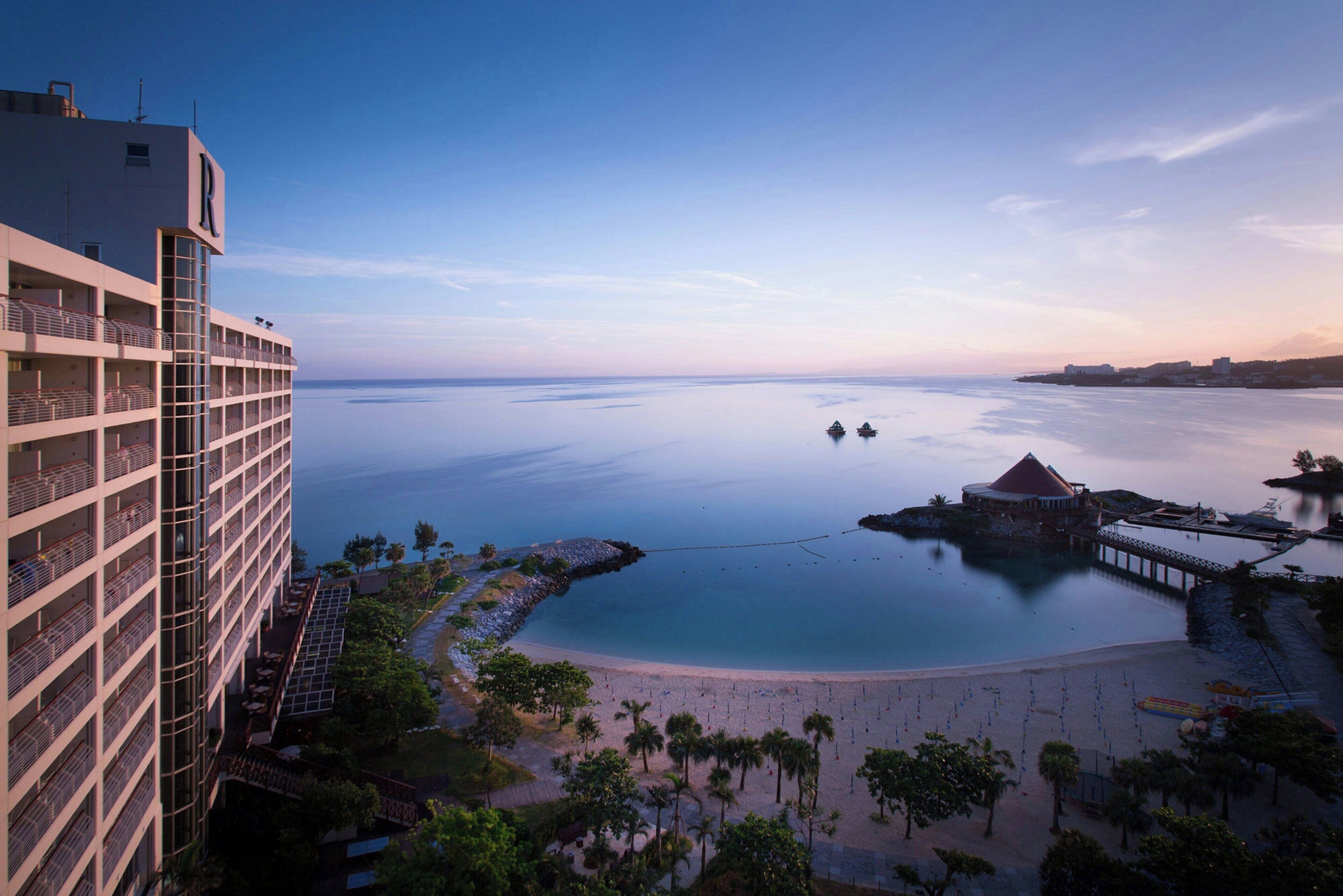 A resort with a large building, a beach, and a water body.