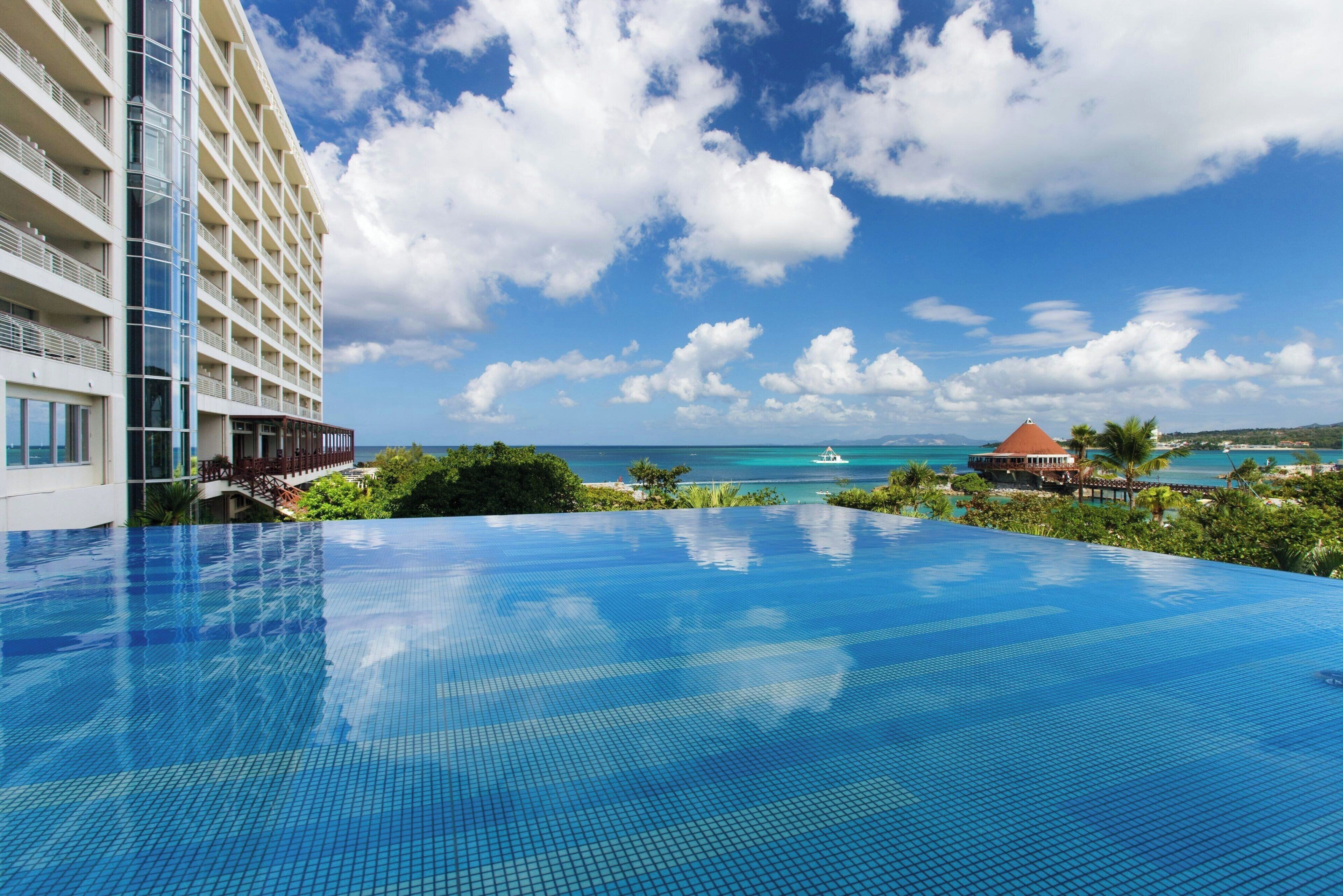 Un hotel con una amplia piscina infinita con vistas a una playa y al océano.
