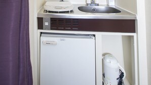 Une petite salle de bain comprenant un lavabo, un petit réfrigérateur et un miroir au-dessus du lavabo.