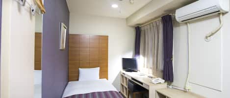 Een hotelkamer met een bed, een bureau, een televisie, een airconditioning en een magnetron.
