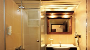 A bathroom with a glass shower enclosure, a sink with a mirror above it, and a toilet. - Üstün Otel Alsancak (Izmir)