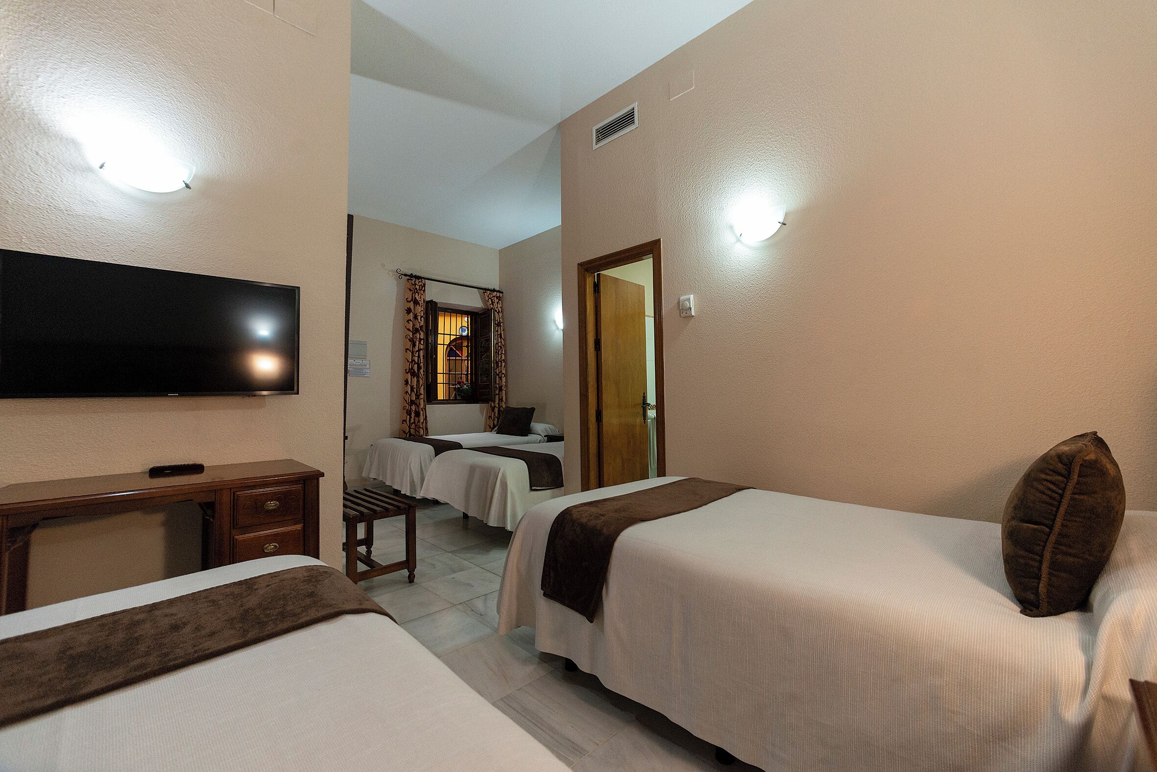 Une chambre d’hôtel avec deux lits, un bureau, une télévision et une salle de bain avec douche et toilettes.