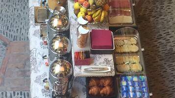 Une table de buffet proposant une variété d’aliments, notamment des fruits, des pâtisseries et des condiments.