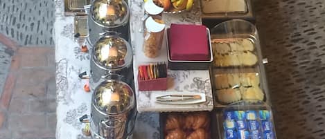 A buffet table with various food items including fruits, pastries, and condiments.