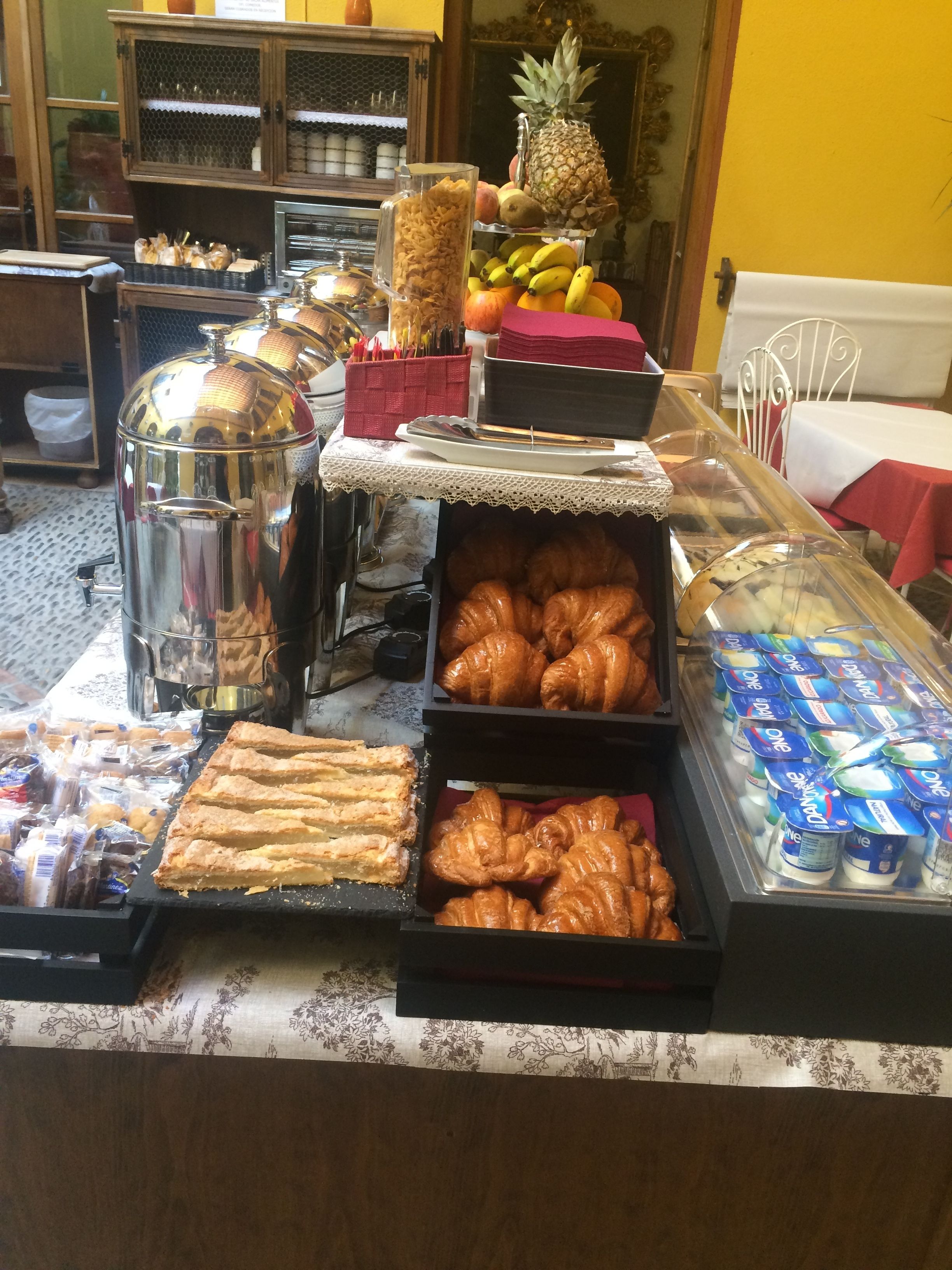 Un bufé de desayuno con diversos pasteles, frutas y productos lácteos.