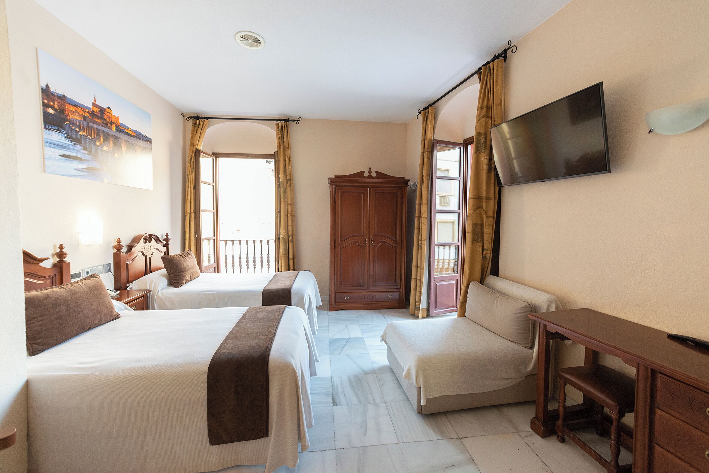 Una habitación de hotel con dos camas, un armario de madera, un televisor y un escritorio.