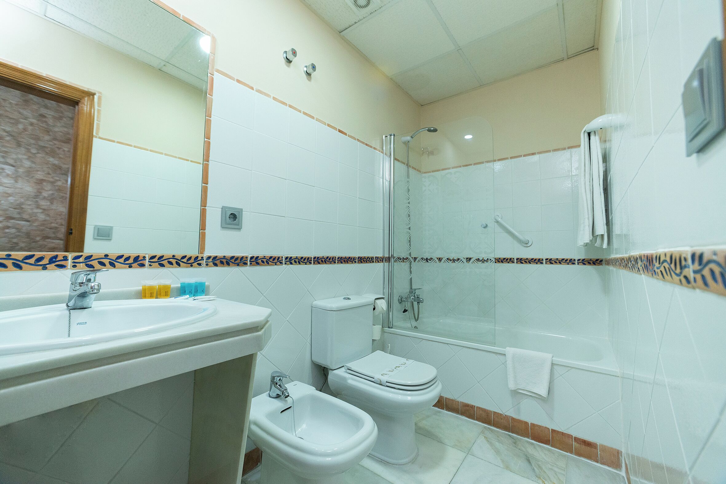 A bathroom with a sink, bidet, toilet, and shower.