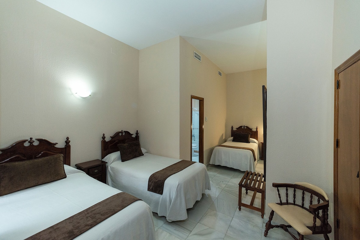 Ein Hotelzimmer mit zwei Betten, einem Holzstuhl und einem kleinen Tisch.