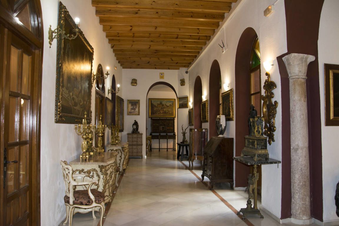 Un pasillo con muebles ornamentados, techo de madera y columnas clásicas.