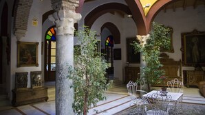 Un intérieur caractérisé par des plafonds en arc de cercle, des colonnes en pierre et un espace de détente central avec des chaises en métal et une table.