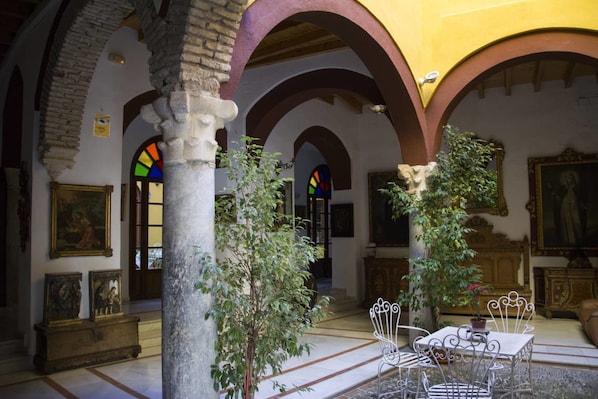 An interior with arched ceilings, stone columns, and a central seating area with metal chairs and a table.