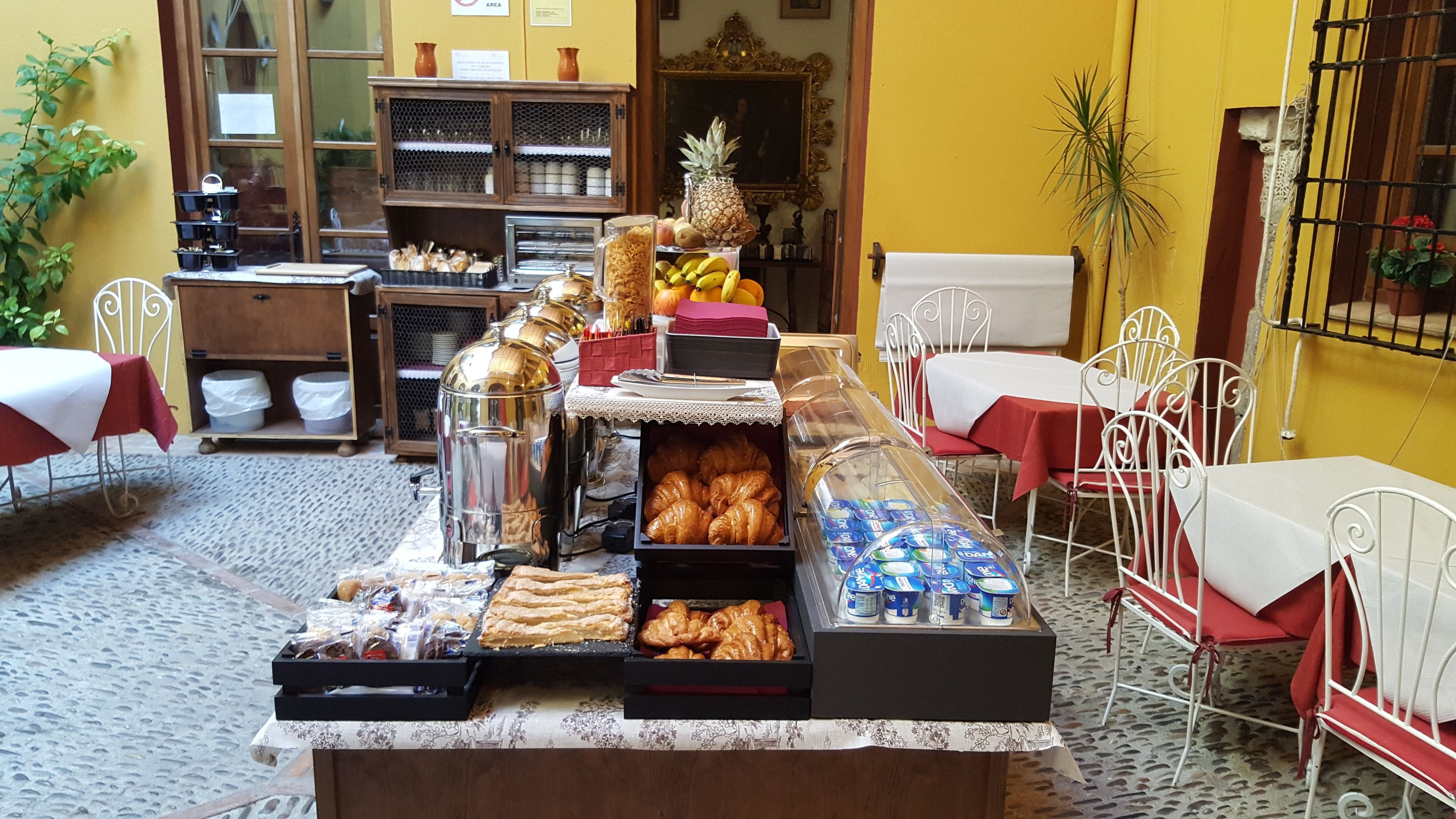 A buffet setup with various food items, including pastries, fruits, and beverages.