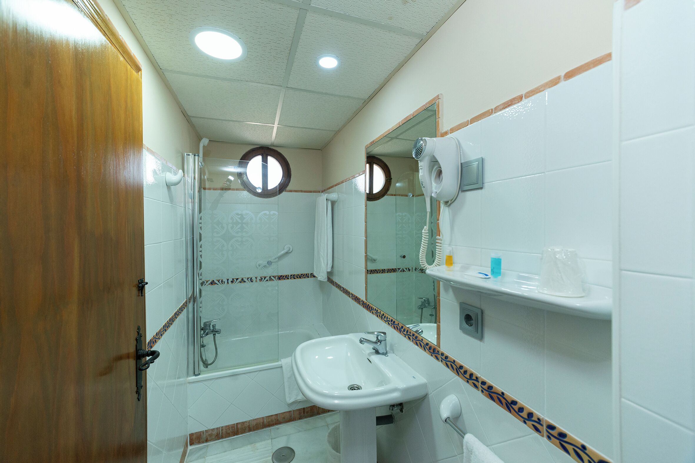 Un baño con lavabo, espejo, secador de pelo y ducha.
