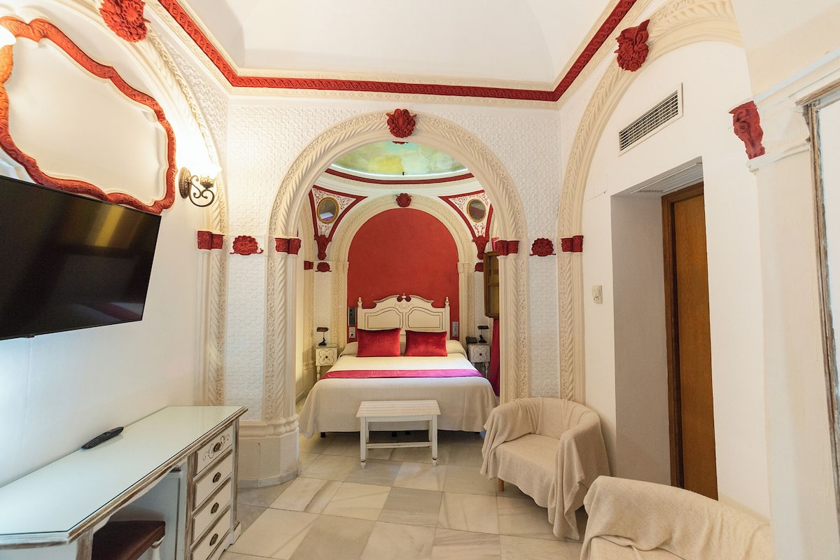 Ein Schlafzimmer mit einem Bett, einem Fernseher, einem Schreibtisch und einem Stuhl.