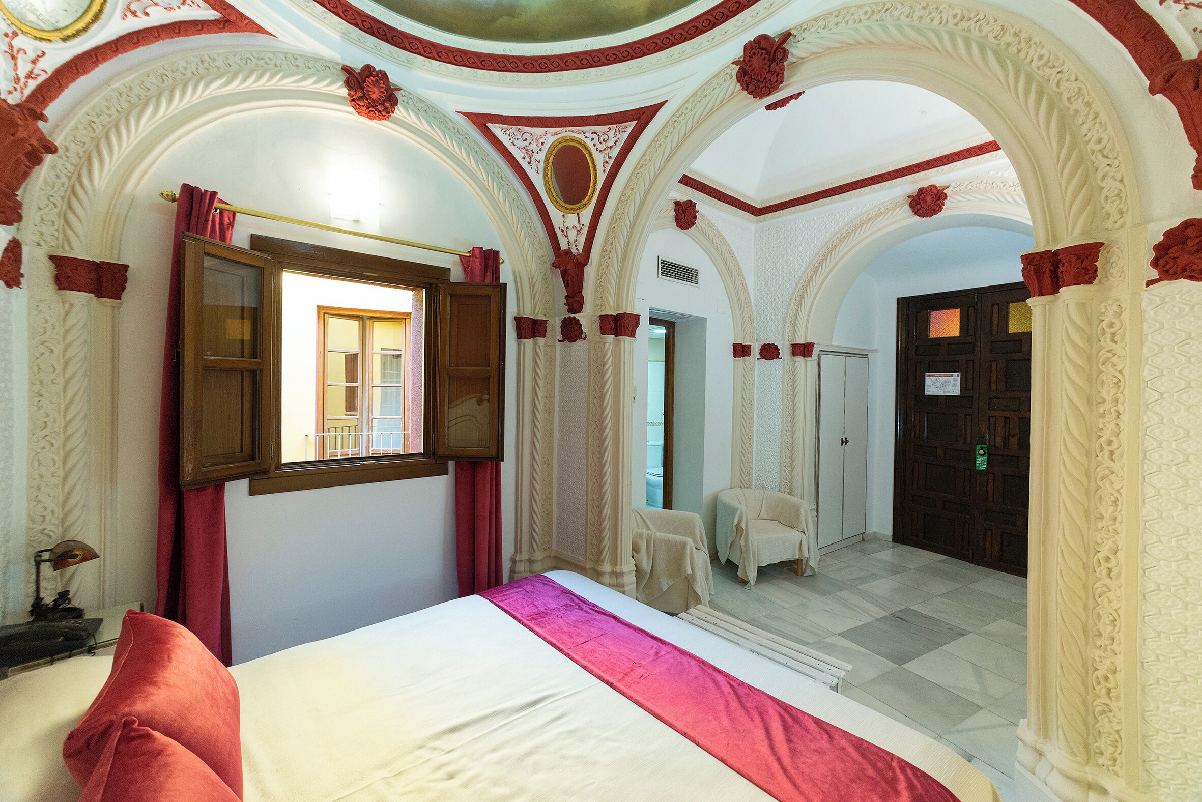 Una habitación de hotel con una cama, una ventana y una puerta.