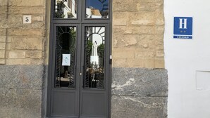 Una puerta de entrada oscura con un panel de vidrio, una pared de piedra y un letrero azul con las letras