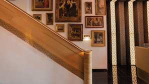 Una escalera con barandilla decorada y una pared decorada con cuadros.