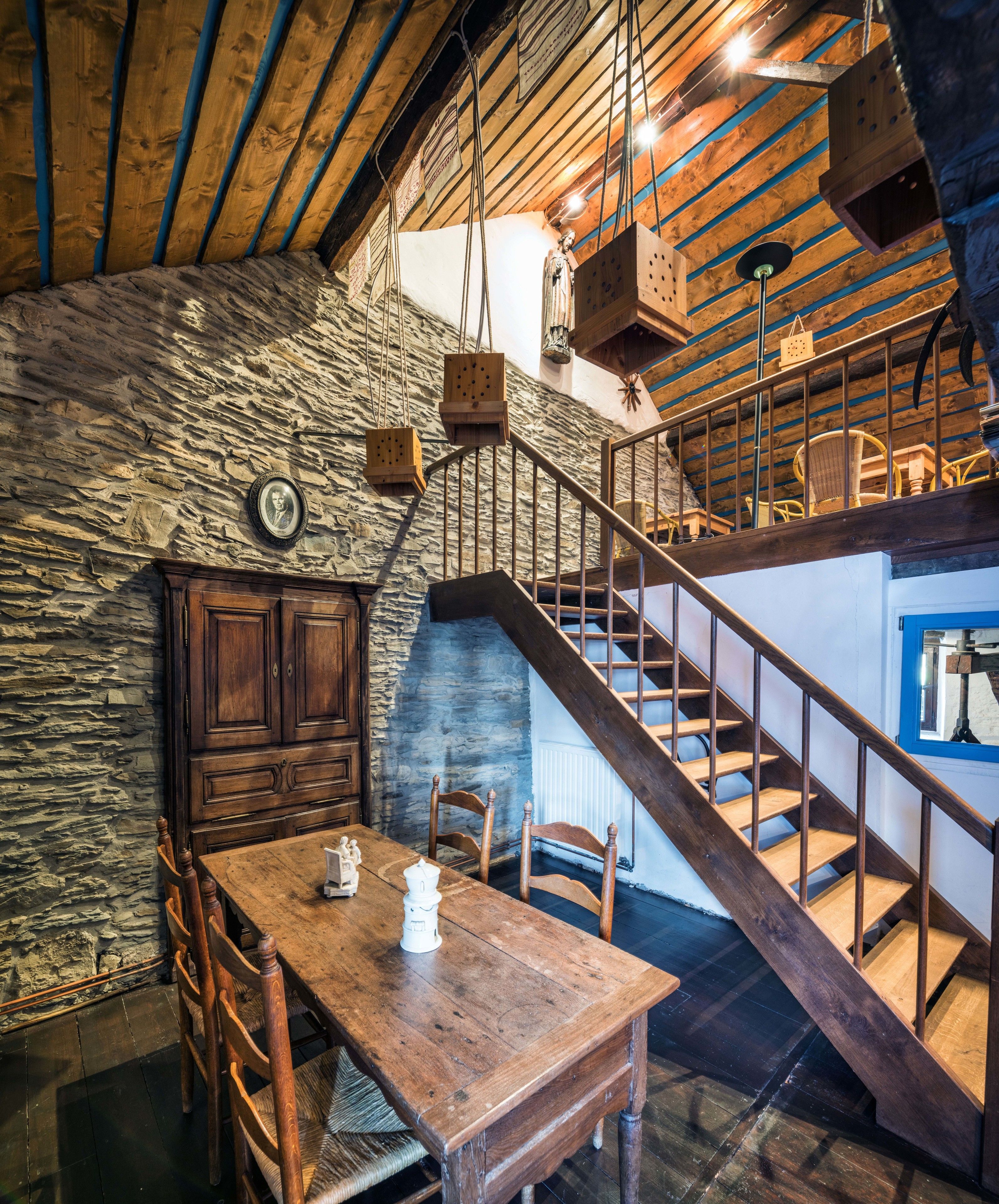 Ein rustikales Interieur mit einer Holztreppe, Steinwänden und einem Essbereich mit Holzzimmermöbeln.