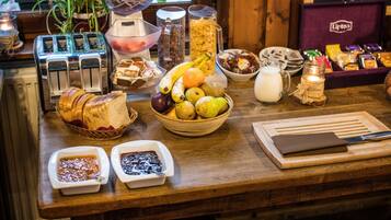 A breakfast buffet with various fruits, bread, and condiments.