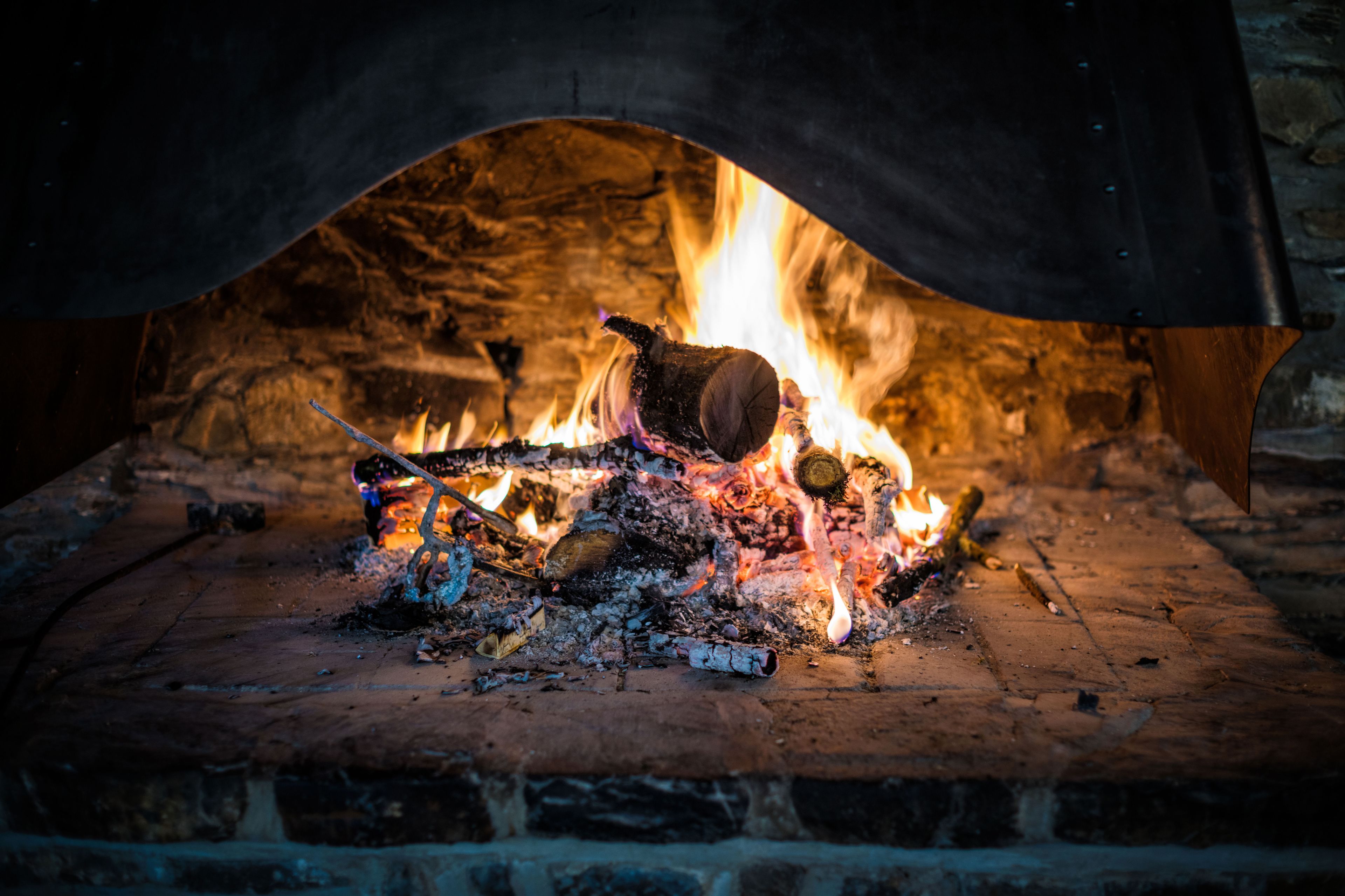 Una chimenea de ladrillo tradicional con fuego encendido en su interior, visible a través de un arco.