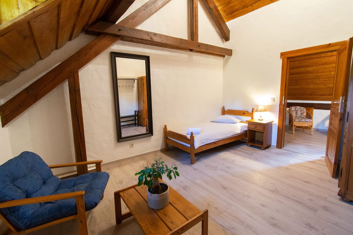 Ein Schlafzimmer mit einem hölzernen Bett, Nachttisch, Lampe, Stuhl und einem Blumentopf.