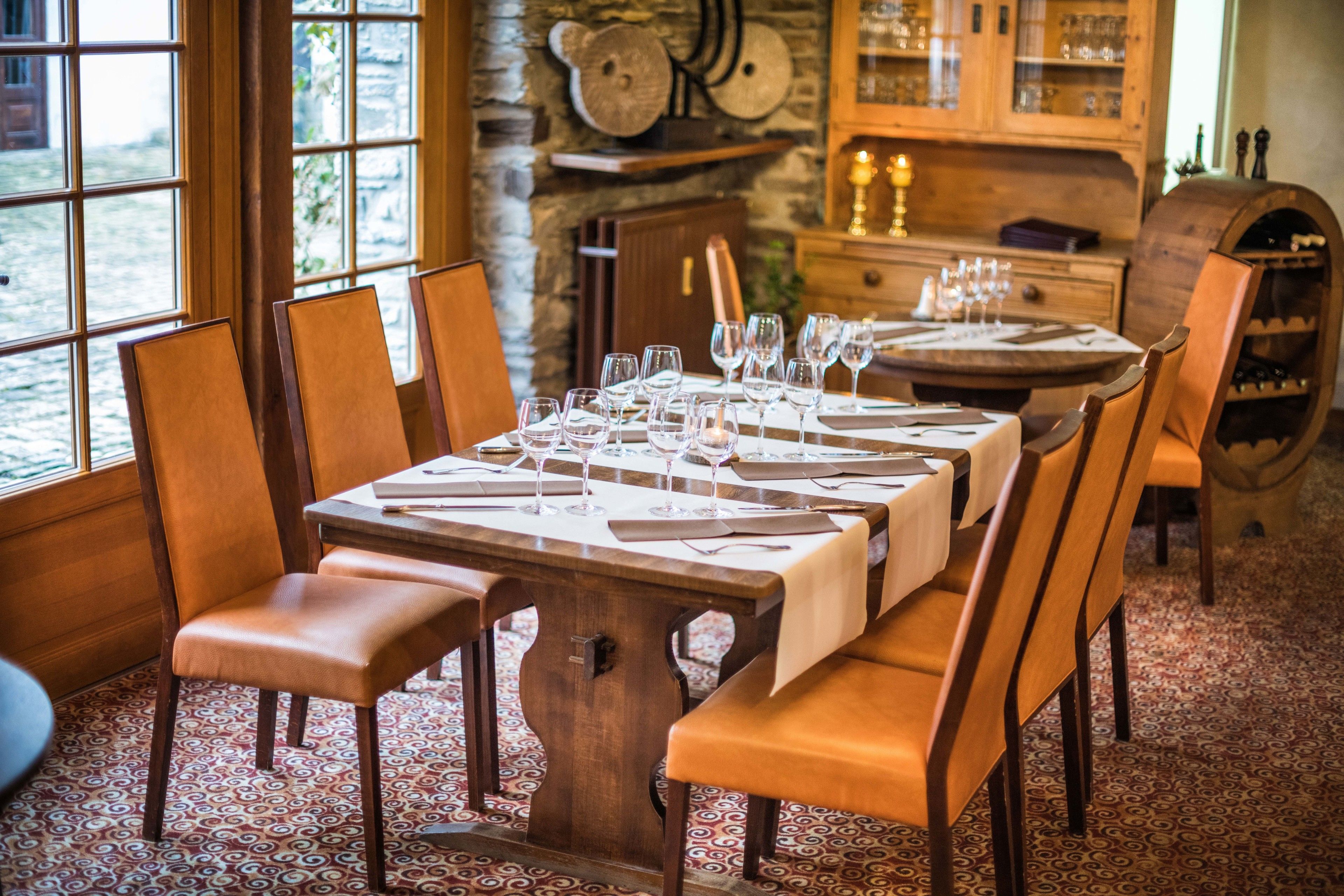 A dining area with a long wooden table set for a meal, surrounded by wooden chairs.