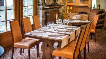 A dining area with a long wooden table set for a meal, surrounded by wooden chairs.