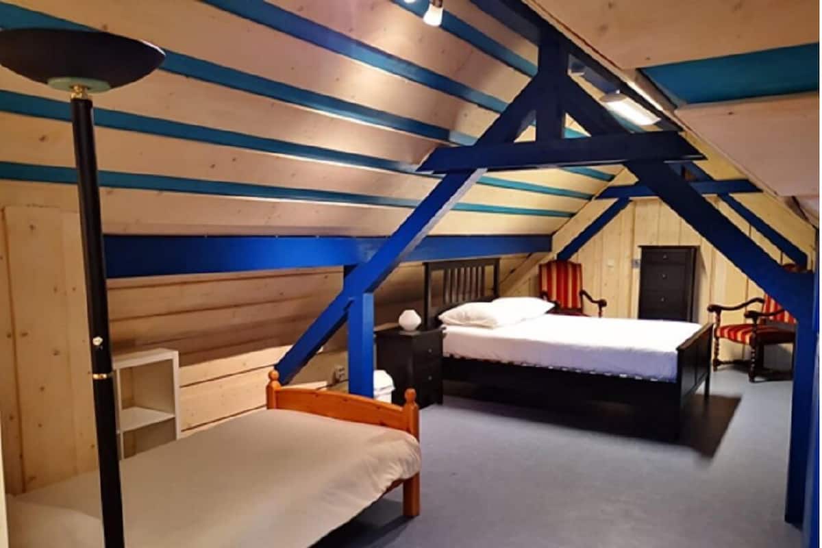 Ein Zimmer mit einem Etagenbett, einem Einzelbett, einem Schreibtisch und einem Stuhl.