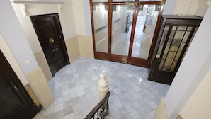 A marble-floored hallway with a black door, a glass door with a frosted pattern, and a dark wooden cabinet. - Lenin Hostel Barcelona (Barcelona)