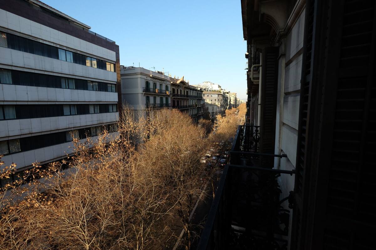 A row of buildings with balconies, a clear sky, and dry vegetation.