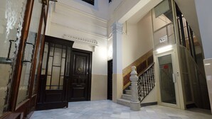 A lobby with a marble floor, a black door, and a staircase with a metal railing. - Lenin Hostel Barcelona (Barcelona)