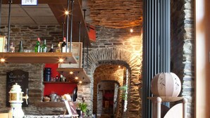 Eine gemütliche Bar mit Steinwand, Holztresen und rustikalem Ambiente.