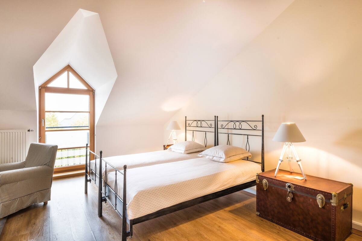 A bedroom with a bed, a chair, a lamp, and a suitcase.