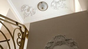 En trappe med detaljerede metalgelændere og en dekorativ vægdekoration.
