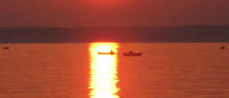 A sunset over a calm body of water with boats.
