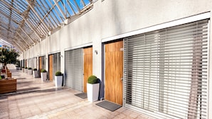 A covered walkway with large windows, potted plants, and closed doors. - Adresa Suites (Belgrade)