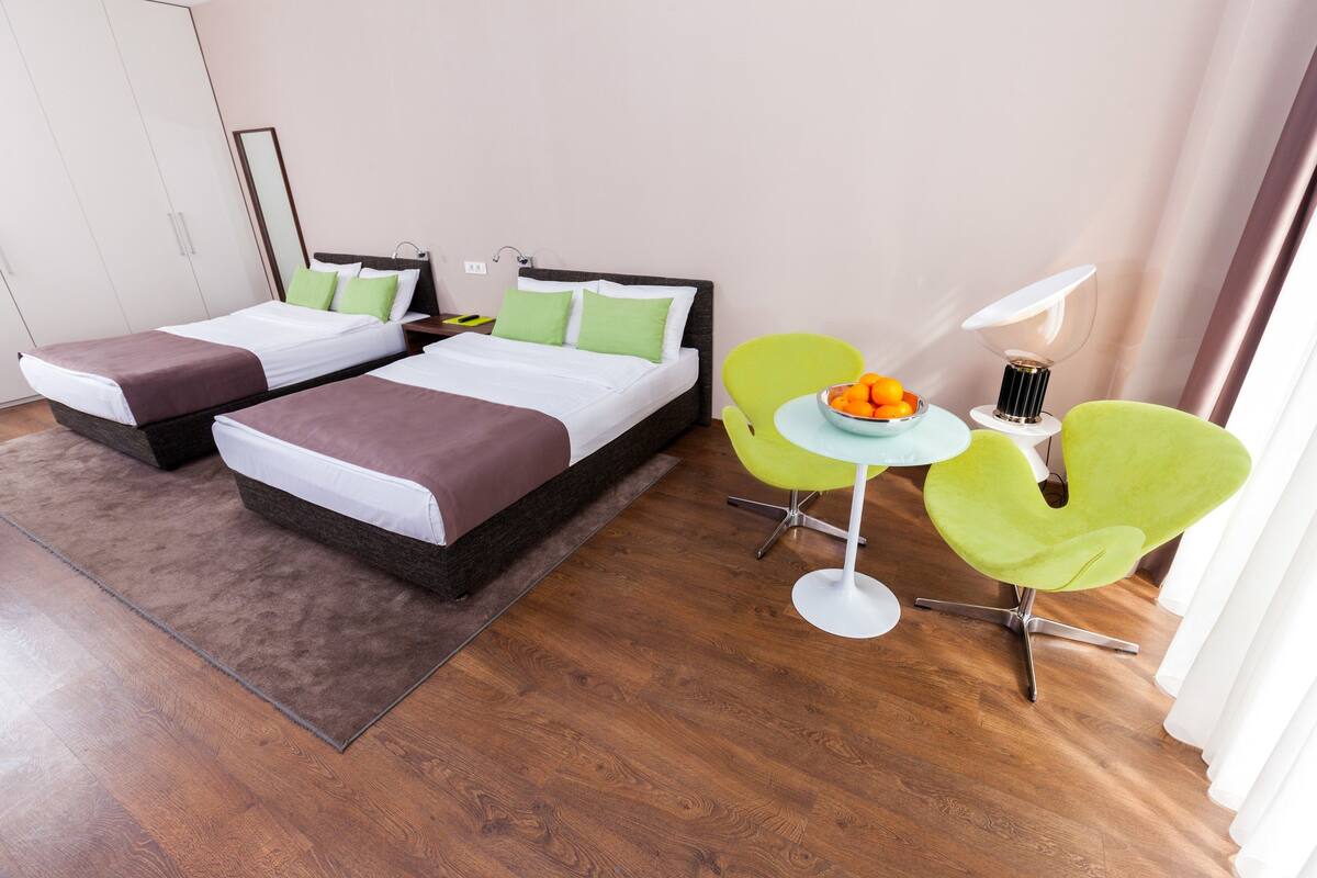 Habitación de hotel con dos camas, una mesita con fruta y una silla.