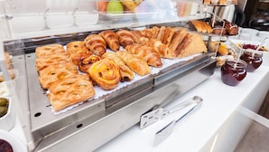 A bakery display with various pastries and a tiered dessert stand. - Adresa Suites (Belgrade)