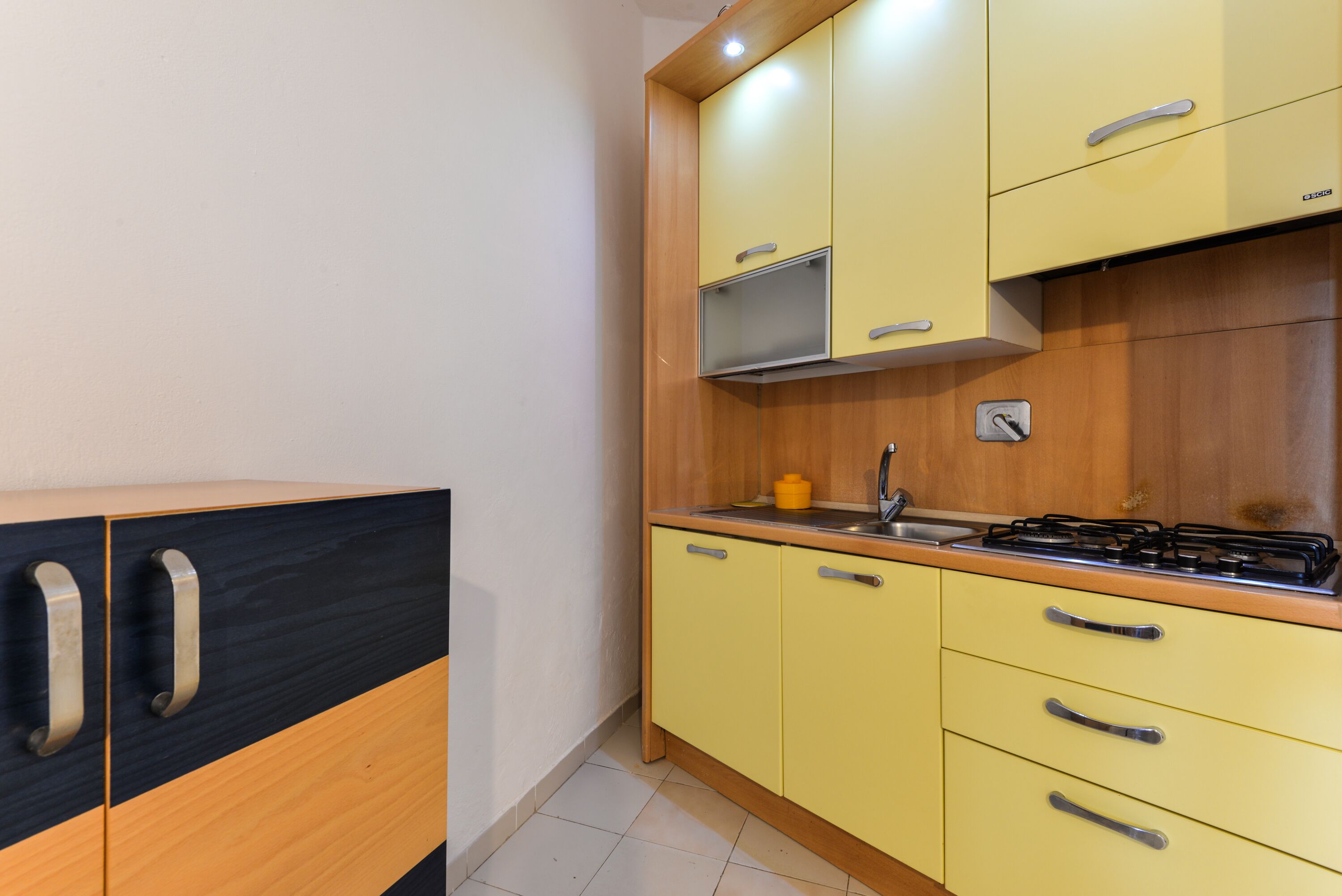 A kitchen with yellow cabinets, a stove, and a sink.